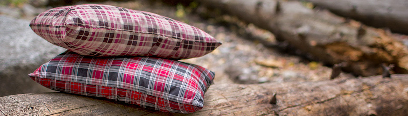 Two TETON Sports Camp Pillows sit together atop a felled log.