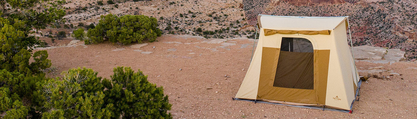 A lone TETON Sports Mesa Canvas Tent sits atop a rocky acrop in the desert.