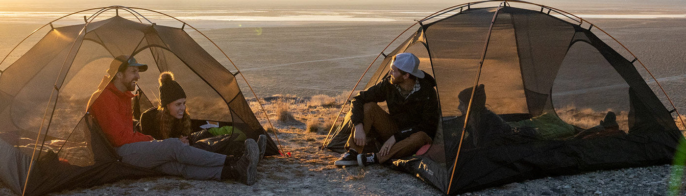 Two couples camp side by side with their matching Mountain Ultra Tents by TETON Sports while the sun sets in the background.