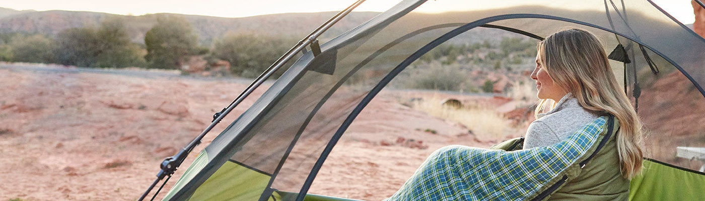 Woman snuggled in a sleeping bag inside a TETON Sports one-person Vista tent.
