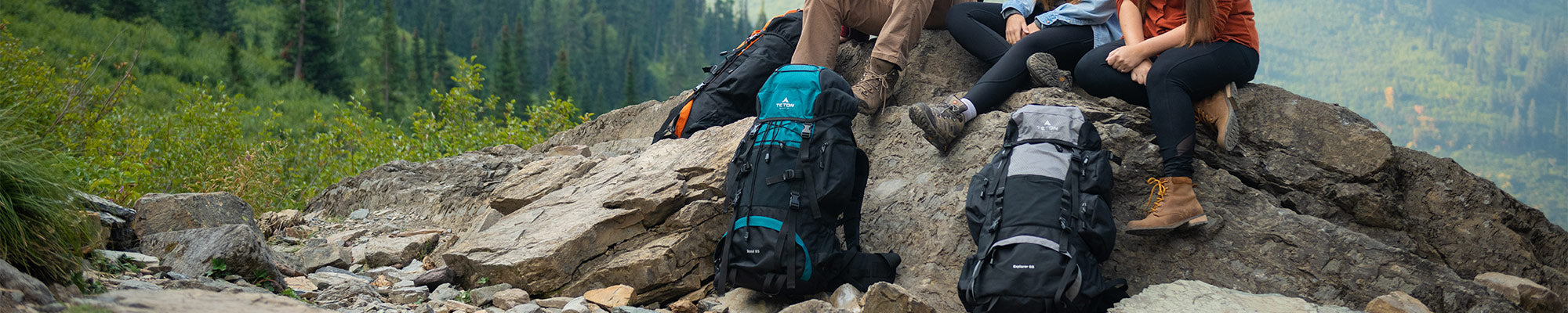 Three friends sit atop a rocky outcrop with their TETON Sports backpacks.