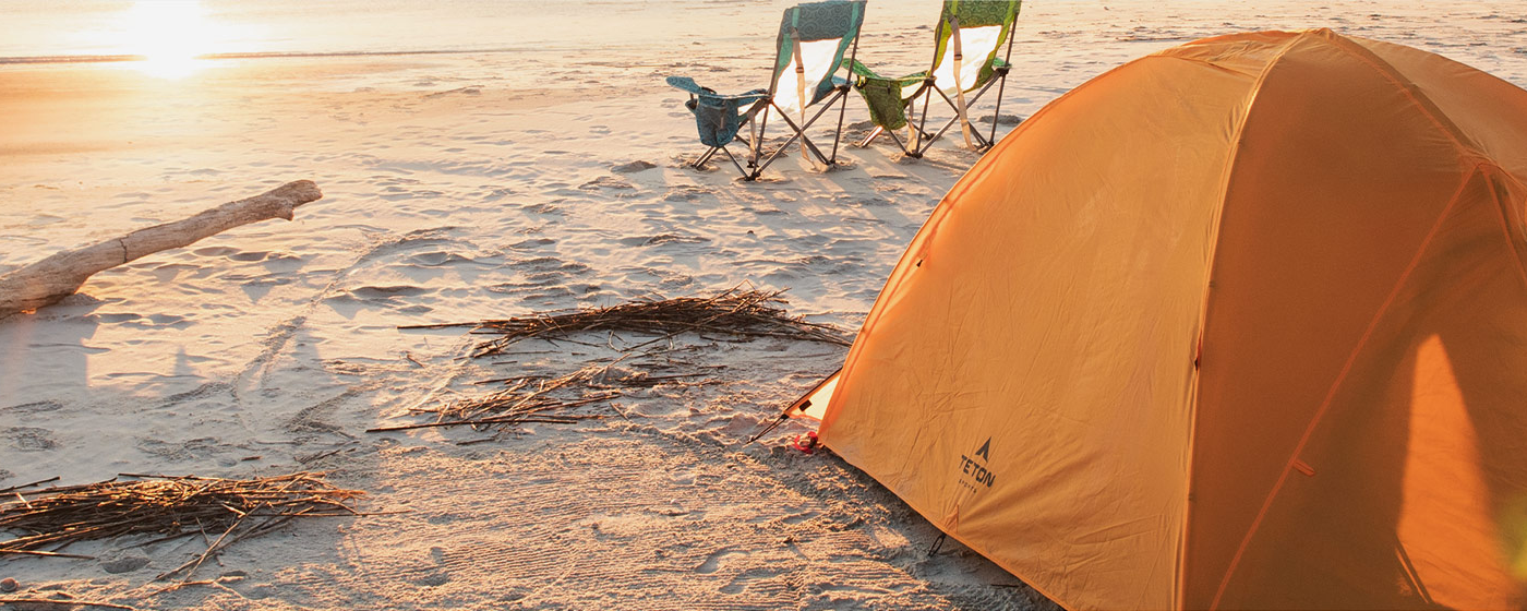 A lone TETON Sports Mountain Ultra Tent is set-up on a deserted beach at sunrise.