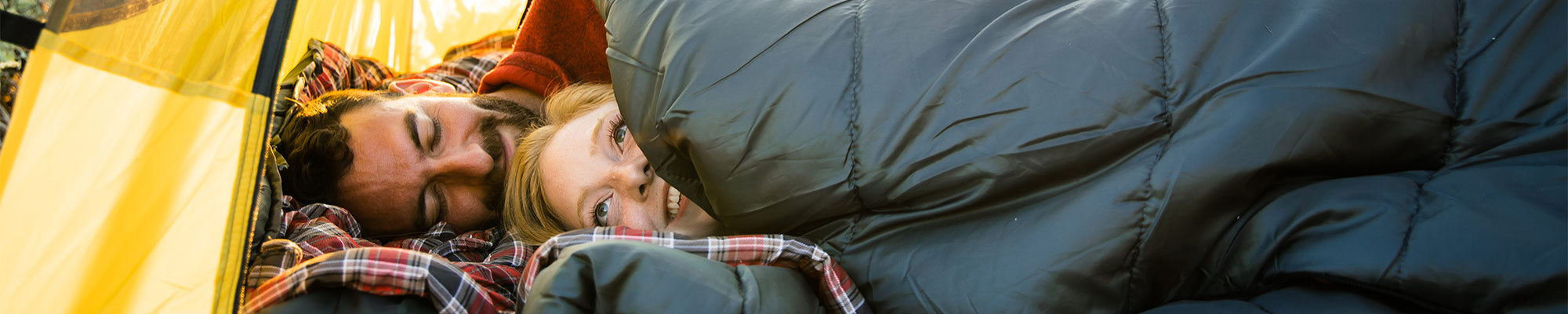 A couple snuggles together inside a TETON Sports Vista Tent while using their Celsius XXL Sleeping Bags.