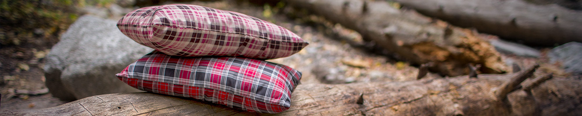 Two TETON Sports Camp Pillows sit together atop a felled log.