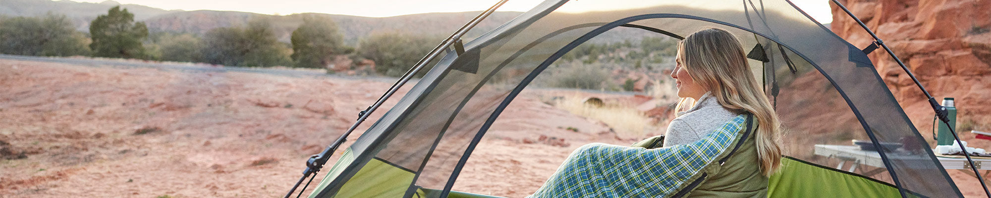 Woman snuggled in a sleeping bag inside a TETON Sports one-person Vista tent.